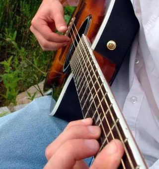 Iemand bespeelt een akoestische gitaar (ter illustratie)