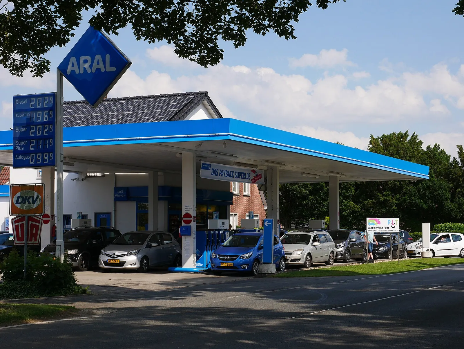 Auto's bij een tankstation met een prijzenbord langs de weg