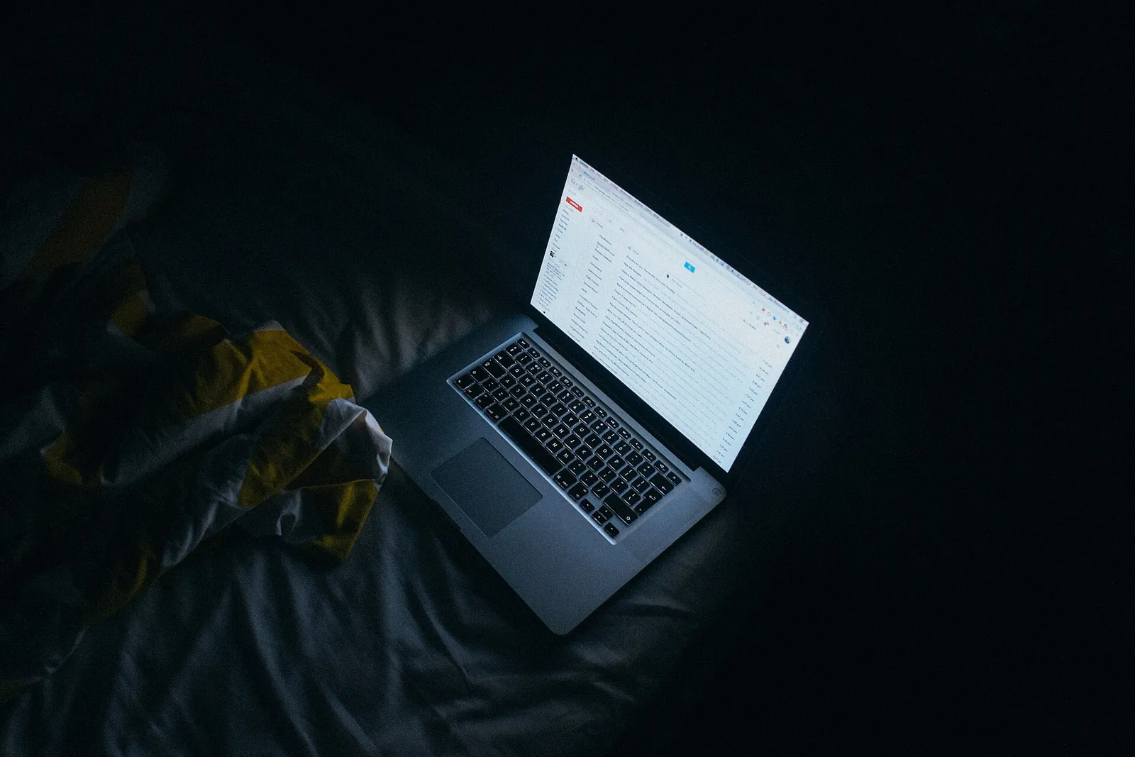 Iemand achter een laptop in het donker (archiefbeeld, ter illustratie)
