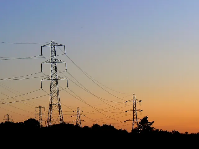 Hoogspanningsmasten bij zonsondergang (ter illustratie)